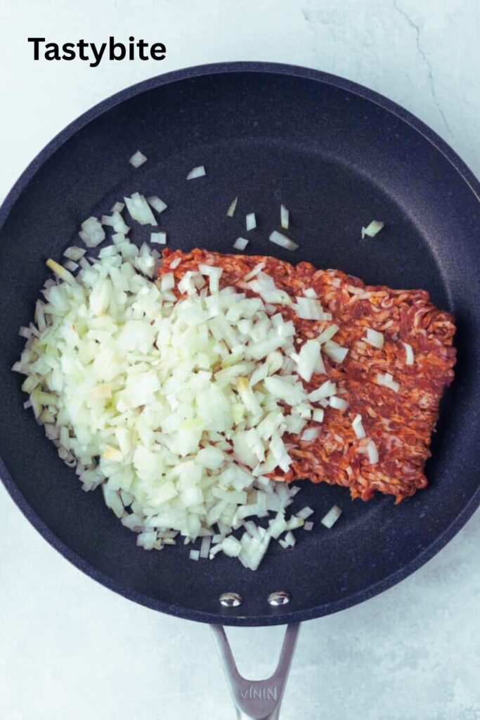 Adding onions and sausage to a skillet
